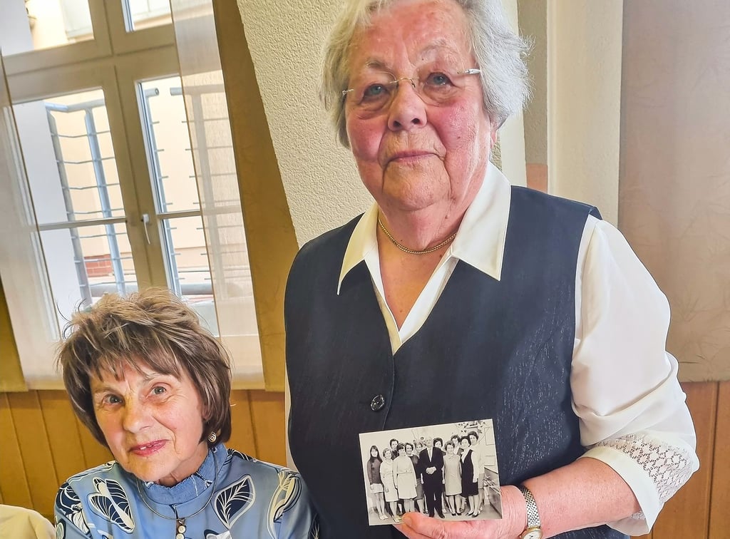 Erdmute Wischer und Erika Rittner (von links). Letztere zeigt ein altes Fotos von Sparkassenmitarbeitern aus den 1960er Jahren. Erika Rittner hat dieses in privaten Fotoalben gefunden.