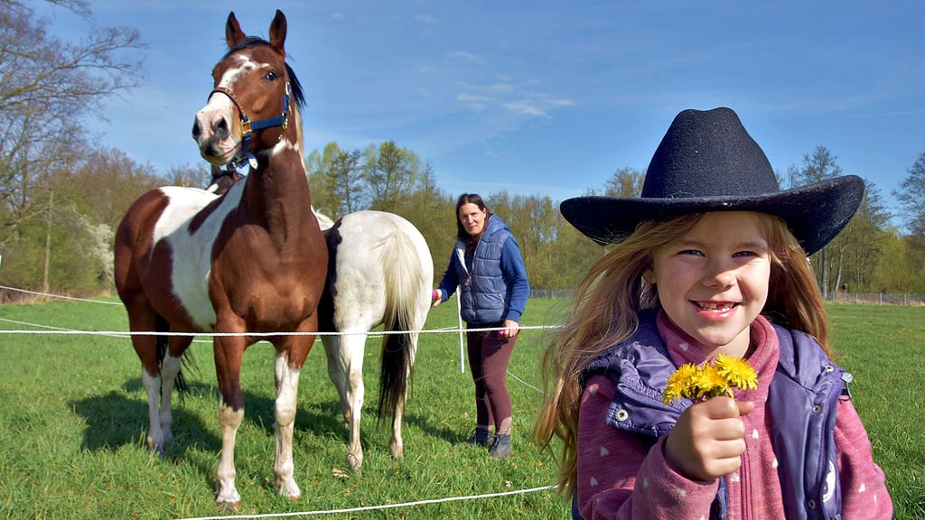 Die fünfjährige Liara hat Löwenzahn gepflückt. Ihre Mutter Melanie Hars bereitet die Pferde Bambam und Smiley zum Wanderritt vor. Die Tour führt am Ufer der Ohre entlang durch den Drömling.