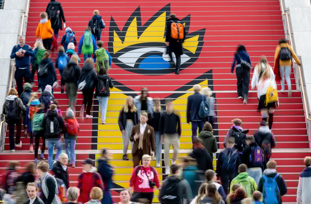 Viel Andrang: Besucherinnen und Besucher der Leipziger Buchmesse gehen zur Eröffnung über eine Treppe mit dem Logo der Buchmesse.