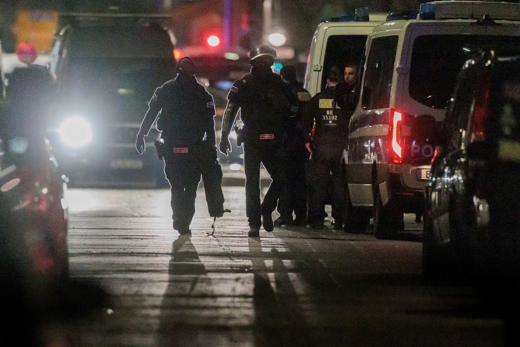 Polizisten gehen zu den Einsatzfahrzeugen nach der Beendigung einer Geiselnahme in einem Geschäft an der Keithstraße.