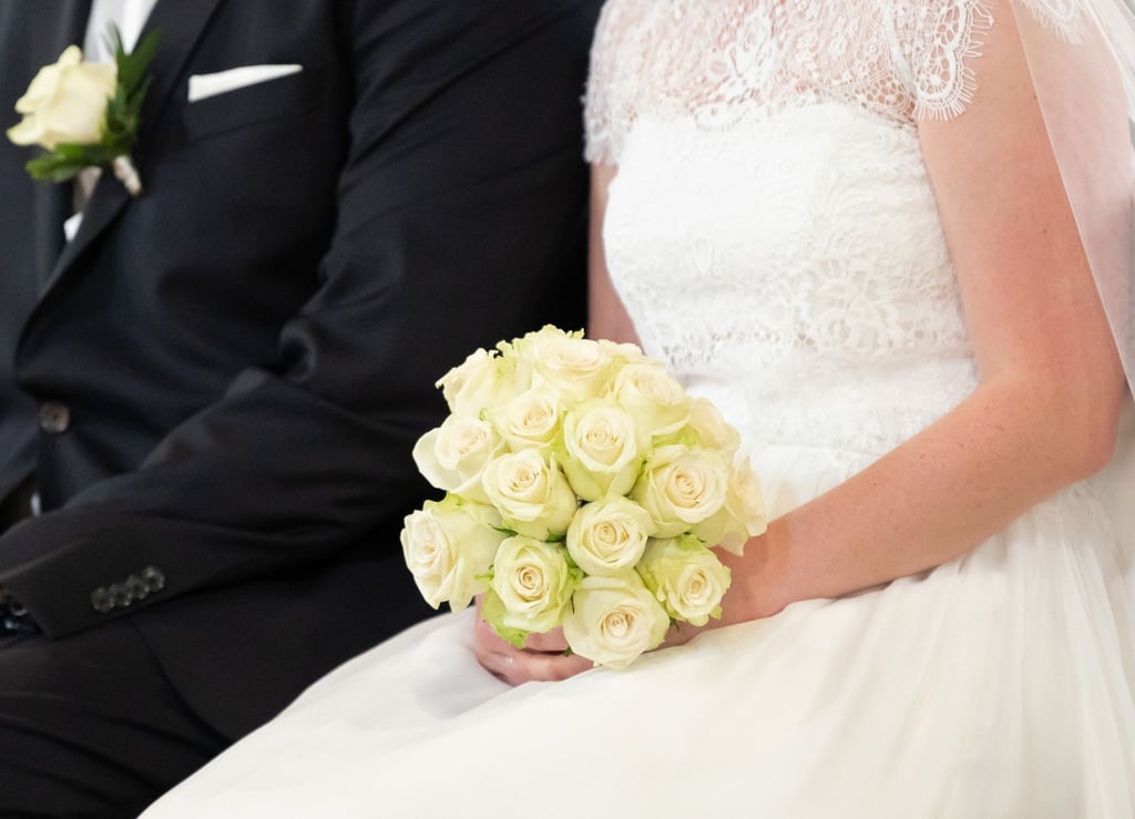 Ein Brautpaar sitzt während ihrer Trauung in der Kirche: In der Corona-Zeit hat ein Paar auf seine Hochzeit verzichtet - was ein Nachspiel hat.