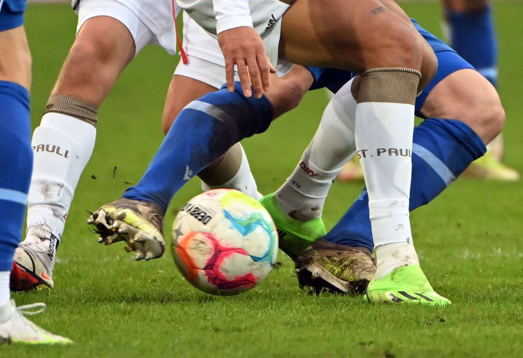 Fußballspieler zweier gegnerischer Mannschaften kämpfen um den Ball.