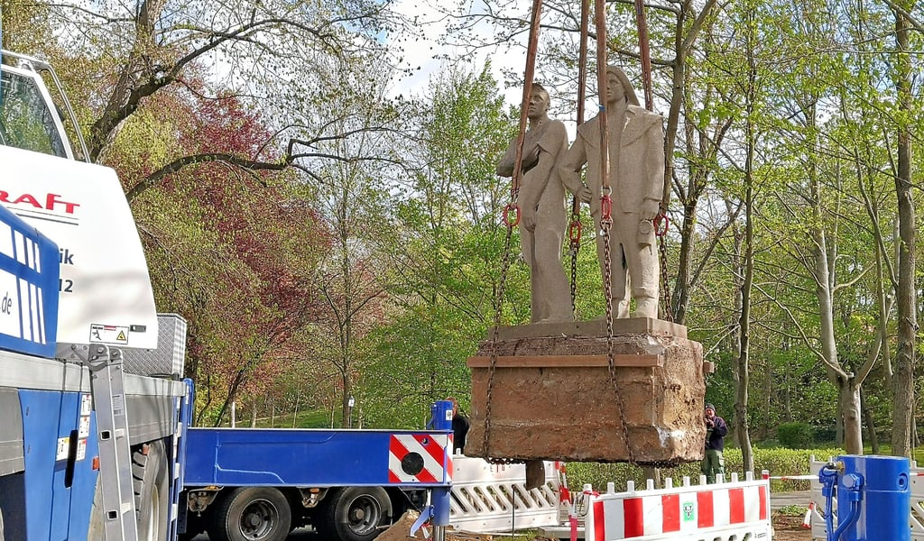 Am Kran hängend schweben die beiden Bergmänner Mittwochvormittag zu ihrem neuen Standort vor dem Rathaus von Holzweißig.