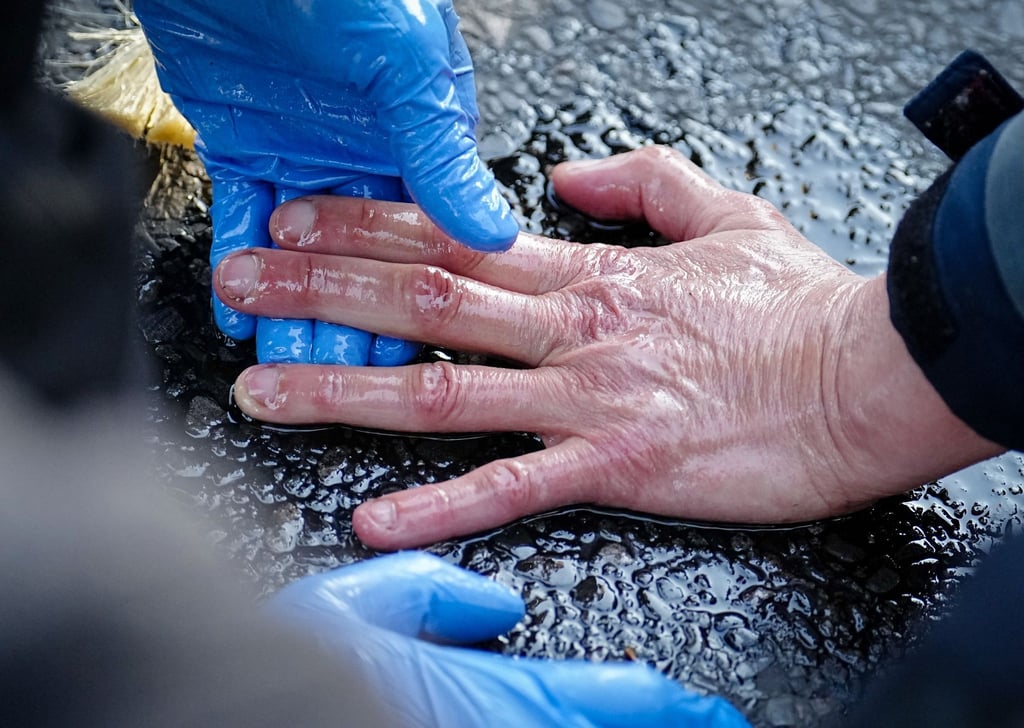 Ein Polizeibeamter löst die Hand eines Klimaaktivisten von der Straße.