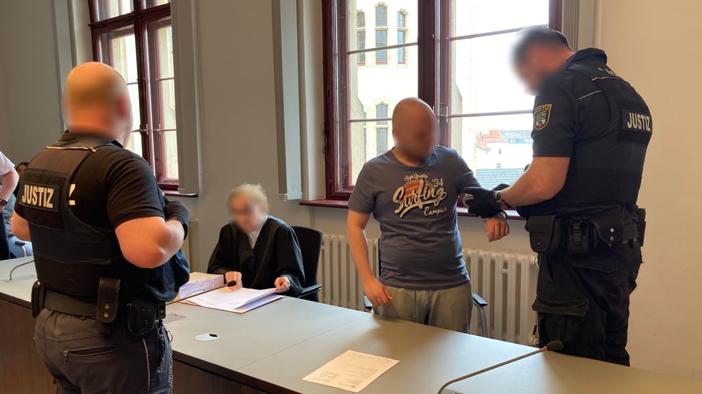 Aus der Untersuchungshaft in den Saal 141 des Landgerichts Halle gebracht: Ein Wachmann nimmt dem Angeklagten die Handschellen ab.
