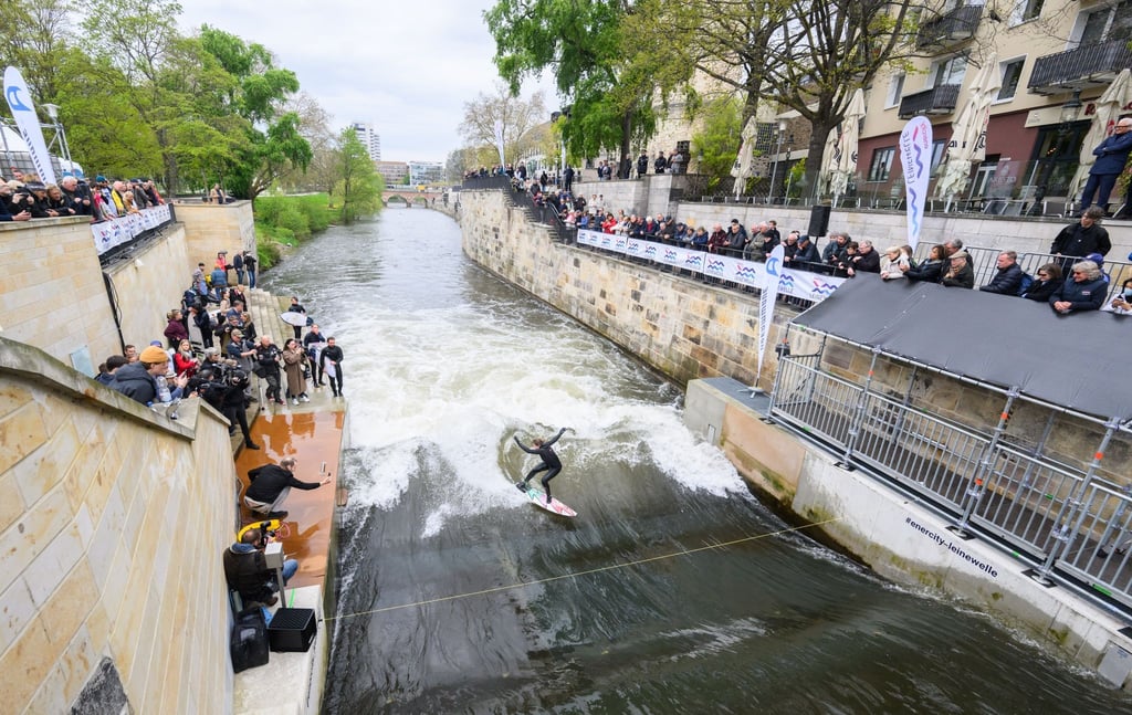 Surfer testen die Leinewelle auf dem Fluss Leine in der Altstadt.