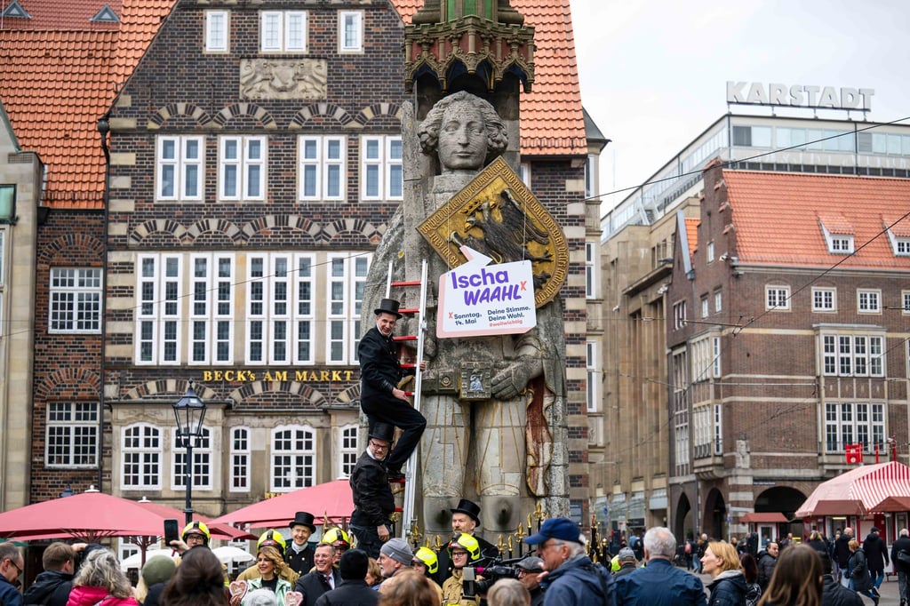 Schornsteinfeger hängen ein Schild mit der Aufschrift „Ischa Waahl!“ an den Bremer Roland.