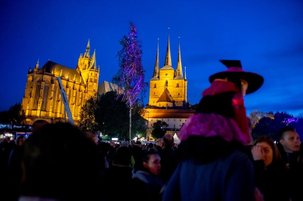 Eine kleine Hexe vor dem Erfurter Dom und Maibaum bei der Walpurgisnacht in Erfurt.