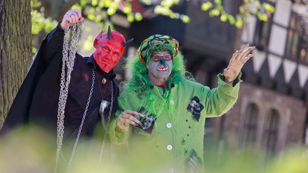 Im Hexen- und Teufelskostüm stehen zwei Walpurgisbesucher in Wernigerode vor der Erstürmung des Rathauses im Stadtzentrum.