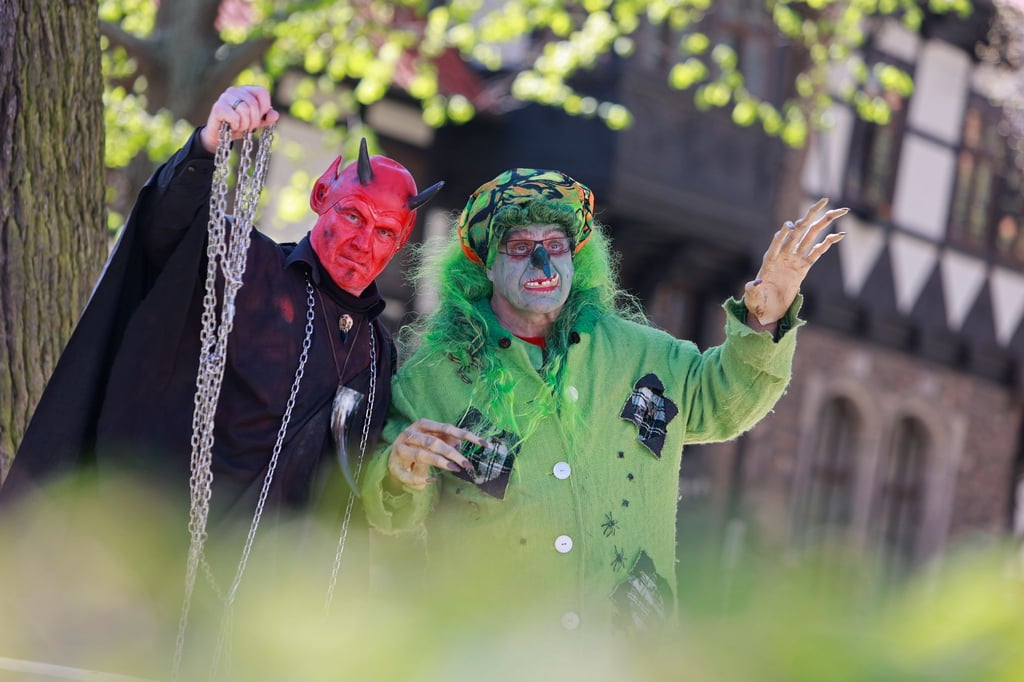 Im Hexen- und Teufelskostüm stehen zwei Walpurgisbesucher in Wernigerode vor der Erstürmung des Rathauses im Stadtzentrum.