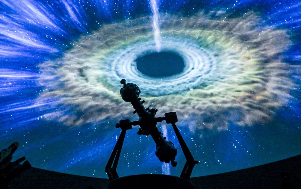 Die Projektion einer Galaxie ist im Sternensaal des Planetariums hinter dem Projektor zu sehen.