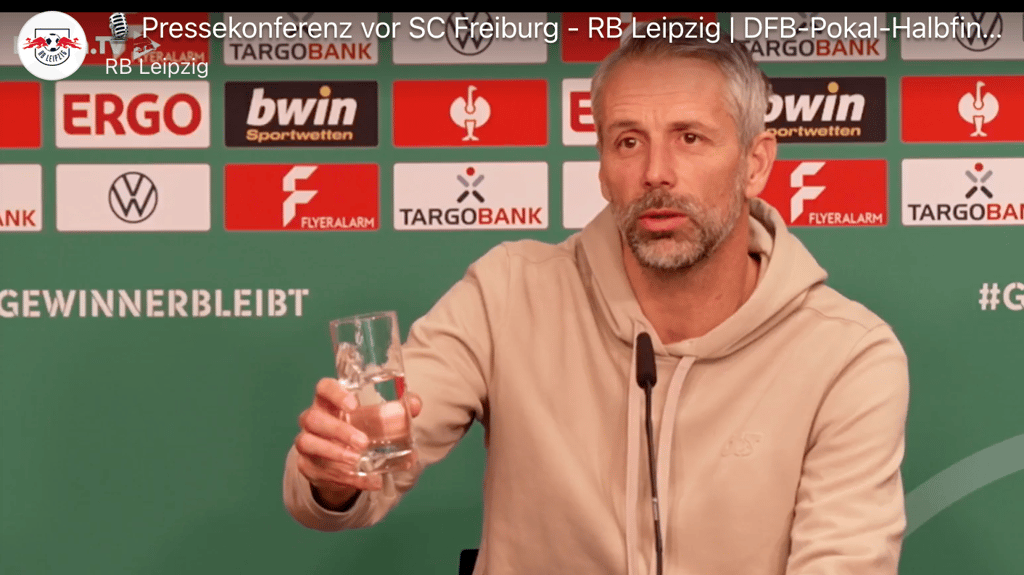 „Mache ich den Eindruck, als ob ich mega angespannt wäre?”: Marco Rose verschüttet Wasser auf dem Pressepodium.