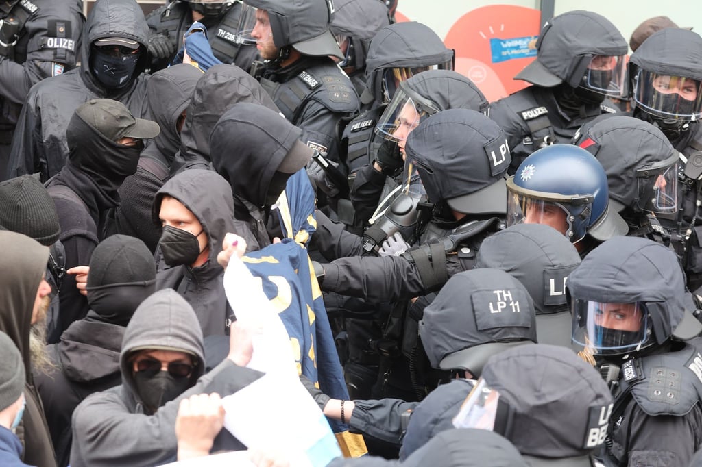 Teilnehmer des linken schwarzen Blockes und Polizeibeamte stehen sich gegenüber.