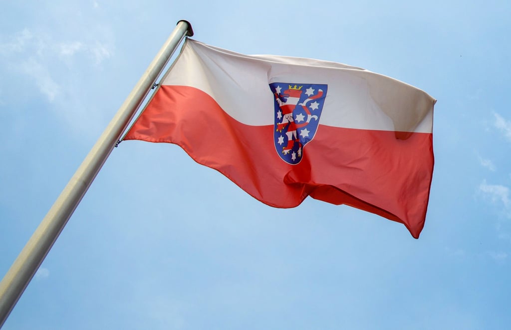 Die Landesfahne von Thüringen weht vor blauem Himmel.