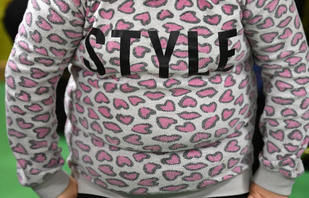 Ein übergewichtiges Kind trägt einen Pulli mit dem Schriftzug „Style“.