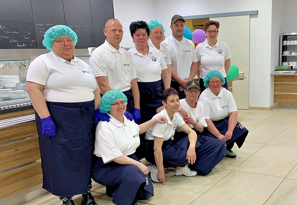 Behinderte Beschäftigte und Mitarbeiter der Lebenshilfe haben sich zum Gruppenfoto in der Cafeteria der Helios-Klinik versammelt.