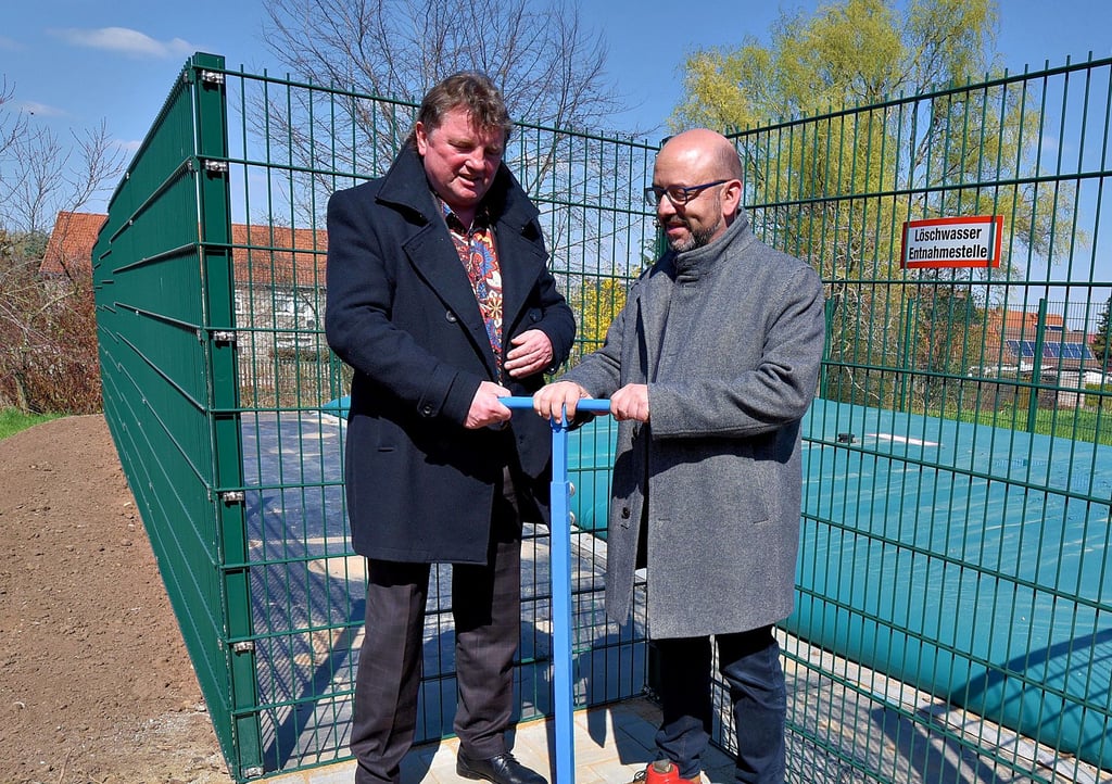 Midewa-Chef Uwe Störzner (l.) und Bürgermeister Andy Haugk nehmen das Löschwasserkissen in der Karl-Marx-Straße in Granschütz in Betrieb.