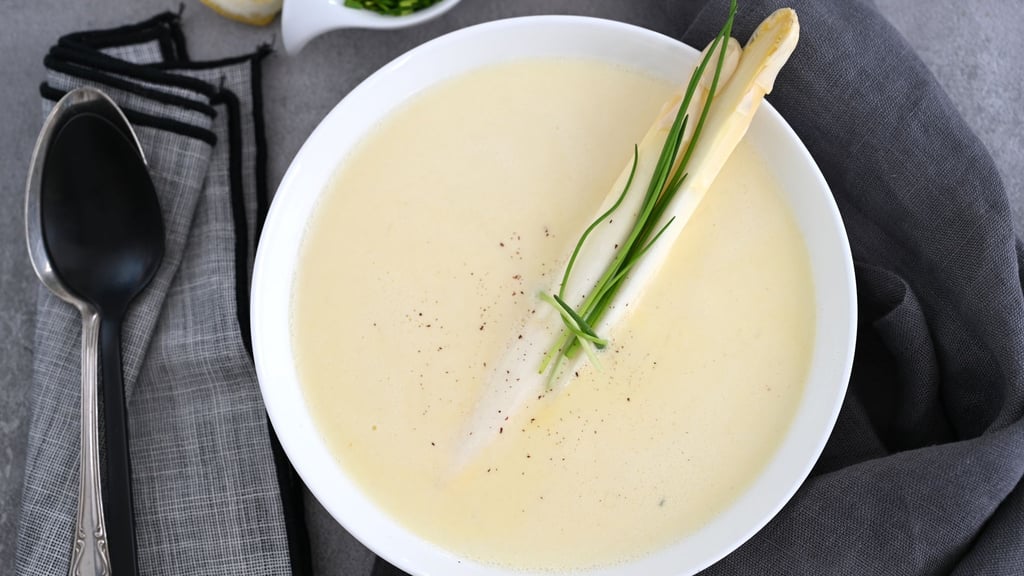 Als Garnitur für das Spargelschaumsüppchen lässt sich Schnittlauch in feine Röllchen schneiden - oder mit zwei Spargelstangen zu einem dekorativen Päckchen schnüren.