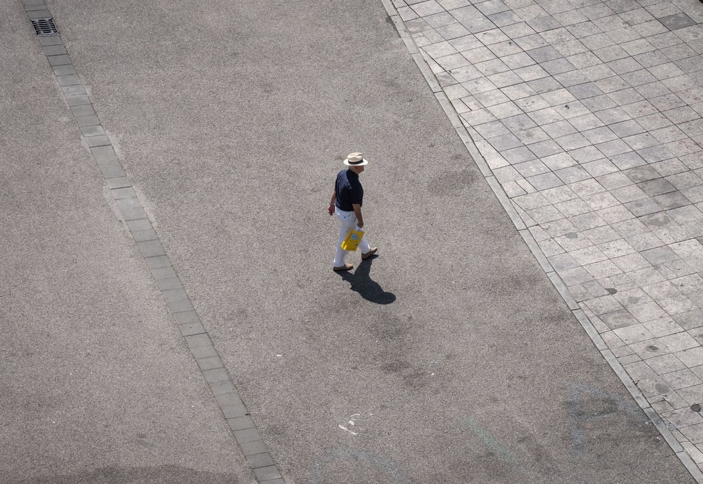 Ein Mann geht über den aufgeheizten Asphalt.