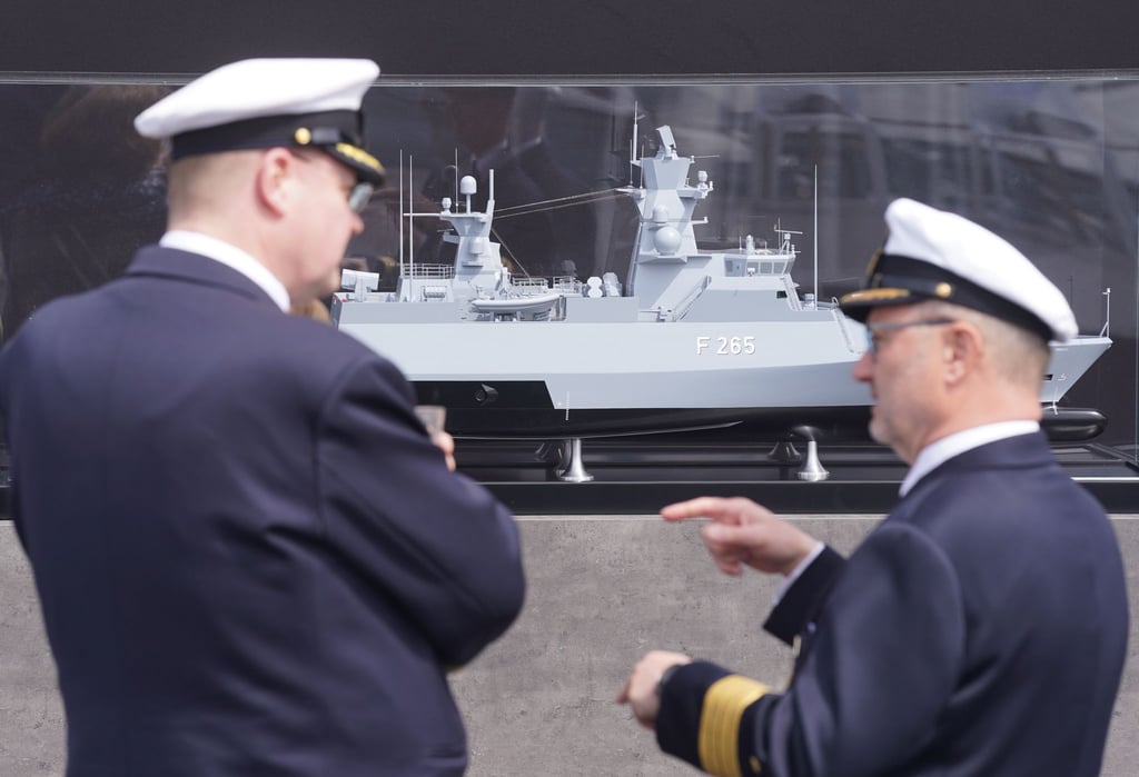 Zwei Marinemitglieder stehen vor einem Modell vor der Taufzeromonie der Korvette F 266 "Emden" auf dem Werftgelände von Blohm+Voss im Hafen.