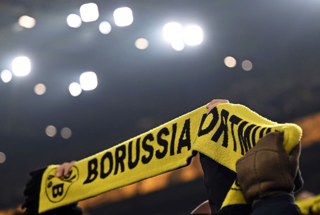 Fans von Dortmund halten einen Schal hoch.