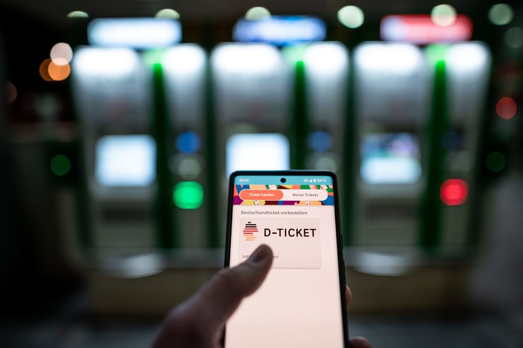 Ein Mann hält ein Mobiltelefon, auf dem das „D-Ticket“ gekauft werden kann.