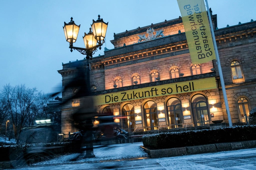 Eine dünne Schneedecke liegt am Morgen vor dem Staatstheater, an dem ein Banner mit der Aufschrift „Die Zukunft so hell“ hängt.