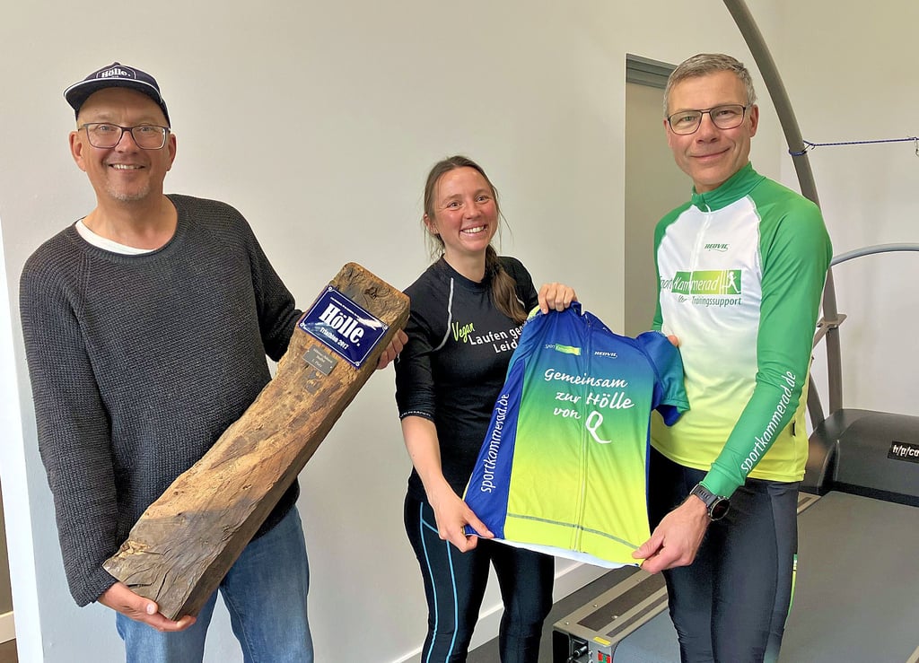 „Gemeinsam zur Hölle von Q“: Jeff Kammerad (von rechts) übergibt Stefanie Eversz das Trikot, mit dem sie bei der „Hölle von Q“ an den Start gegen will. Mark Hörstermann, Organisator des Triathlons, schaut vorbei.