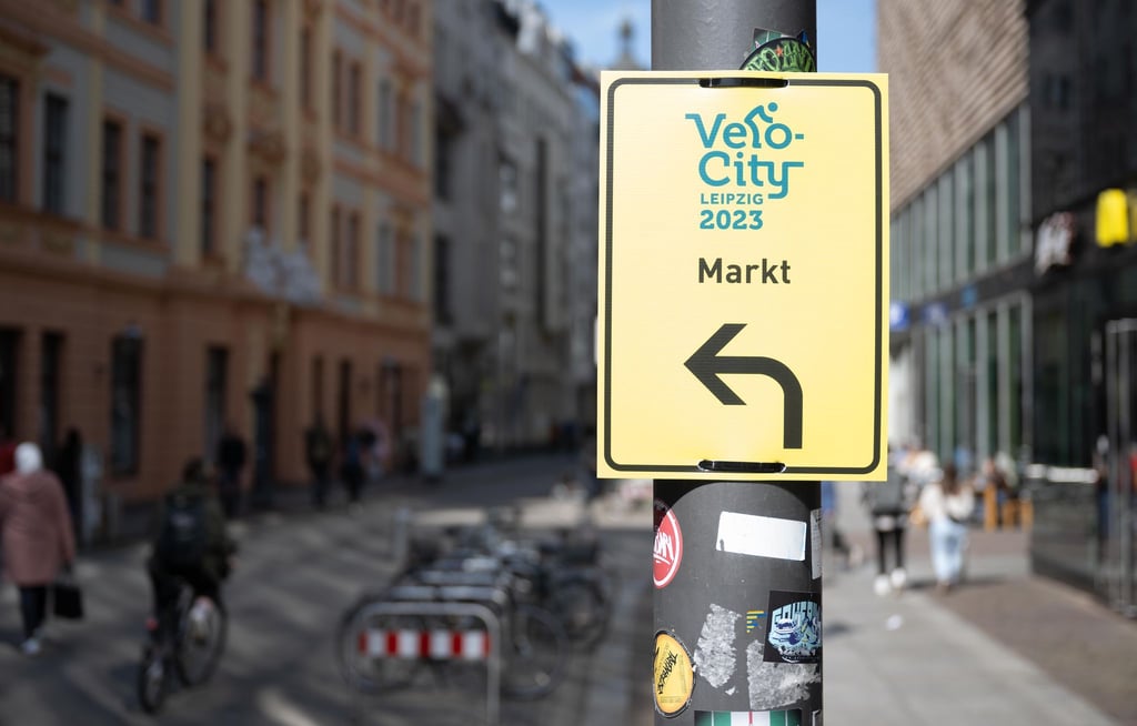 Ein Schild mit dem Logo des Radverkehrskongresses „Velo-city“ markiert einen temporären Radweg im Zentrum von Leipzig.