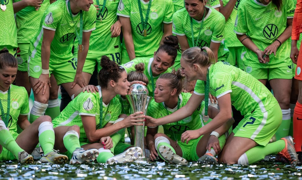 Die Spielerinnen von VfL Wolfsburg jubeln bei der Siegerehrung und küssen den Pokal.