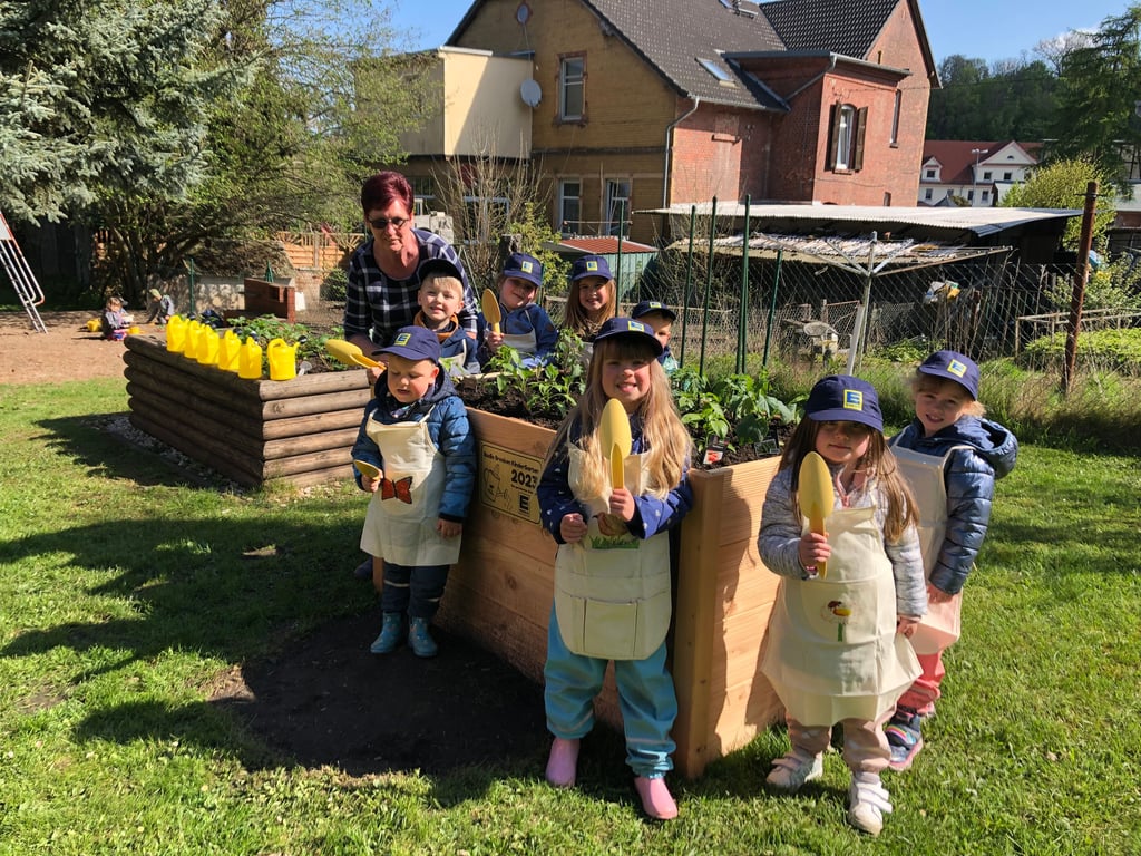 Die Kinder der Kita „Deubener Bergzwerge“ und Leiterin Binka Rümmler freuen sich über das Hochbeet von Radio Brocken und Edeka.