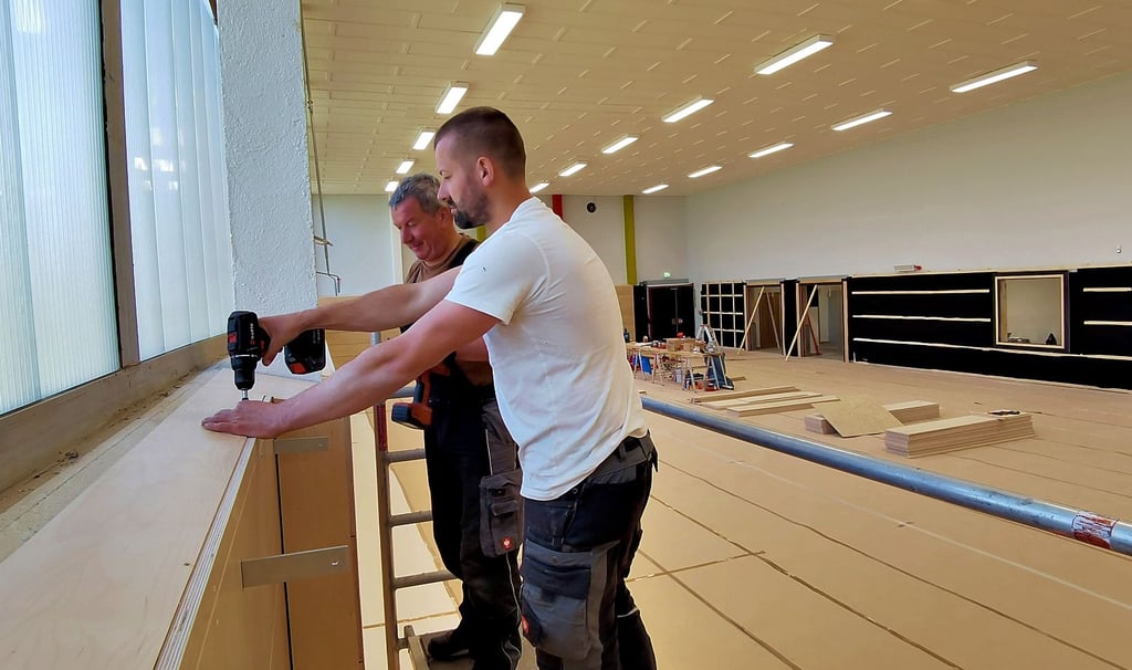 Die Handwerker André Senftleben (vorn) und Mario Pöschmann bauen in der Derenburger Sporthalle eine moderne und 2,20 Meter hohe Prallwand ein.