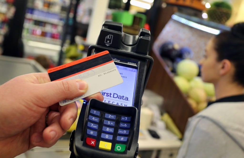 Eine EC-Karte wird an den Bezahl-Terminal an der Kasse eines Supermarktes gehalten.