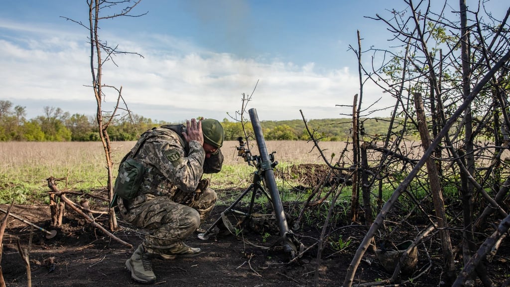 Ein Soldat einer Mörser-Einheit der ukrainischen Streitkräfte hält sich die Ohren zu, während er auf feindliche Stellungen in den Vororten der Stadt Bachmut feuert.