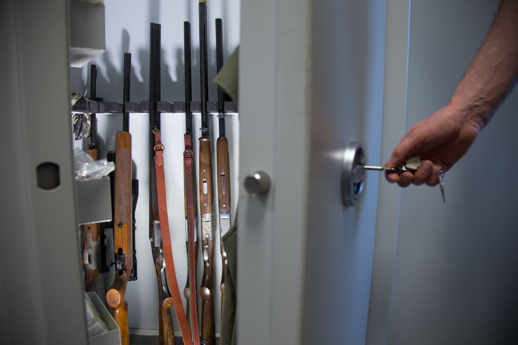 Ein Mann öffnet einen gepanzerten Waffenschrank mit Langwaffen.