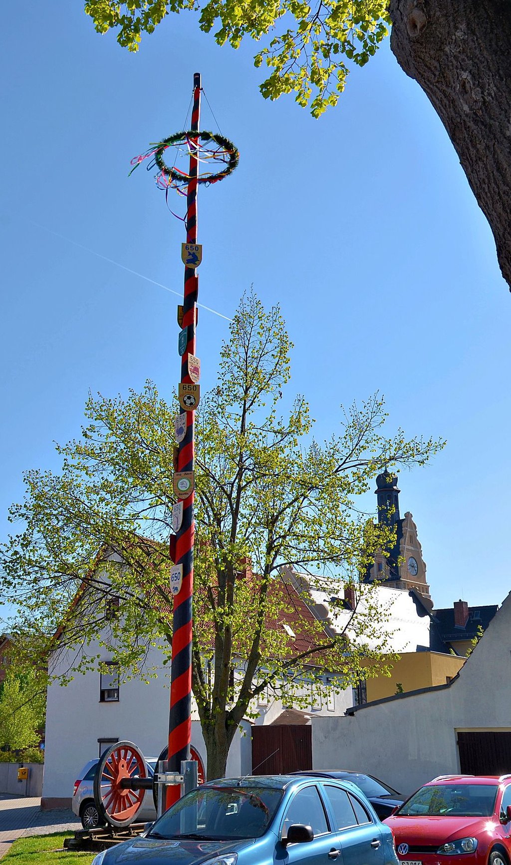 Die Bänder des Güstener Maibaums flattern im Wind. Er steht zwischen Rathaus und St.-Vitus-Kirche gleich neben der Achse, die an Güsten als ehemalige Eisenbahnerstadt erinnert.