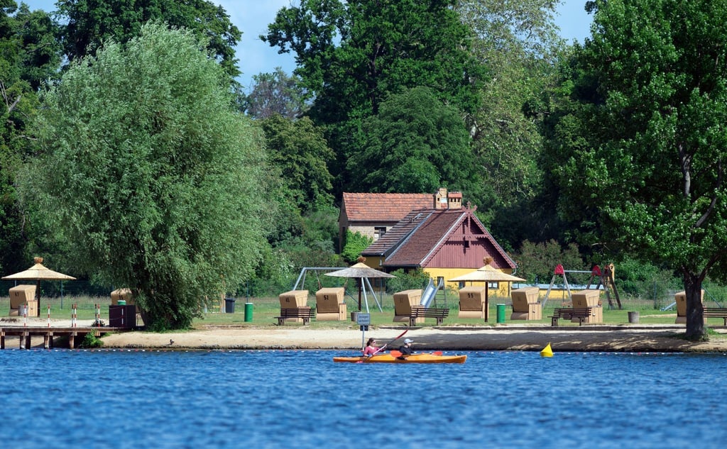 Ein Paddelboot fährt auf dem Tiefen See am Strandbad im Park Babelsberg vorbei.