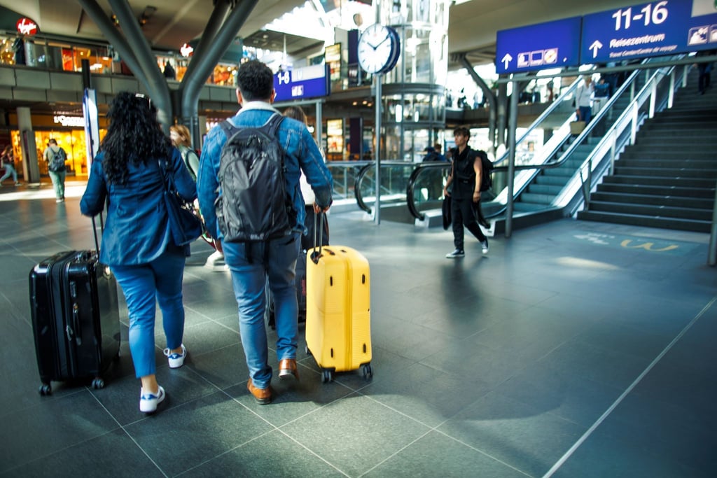 Reisende mit Koffern gehen auf auf dem Berliner Hauptbahnhof umher.