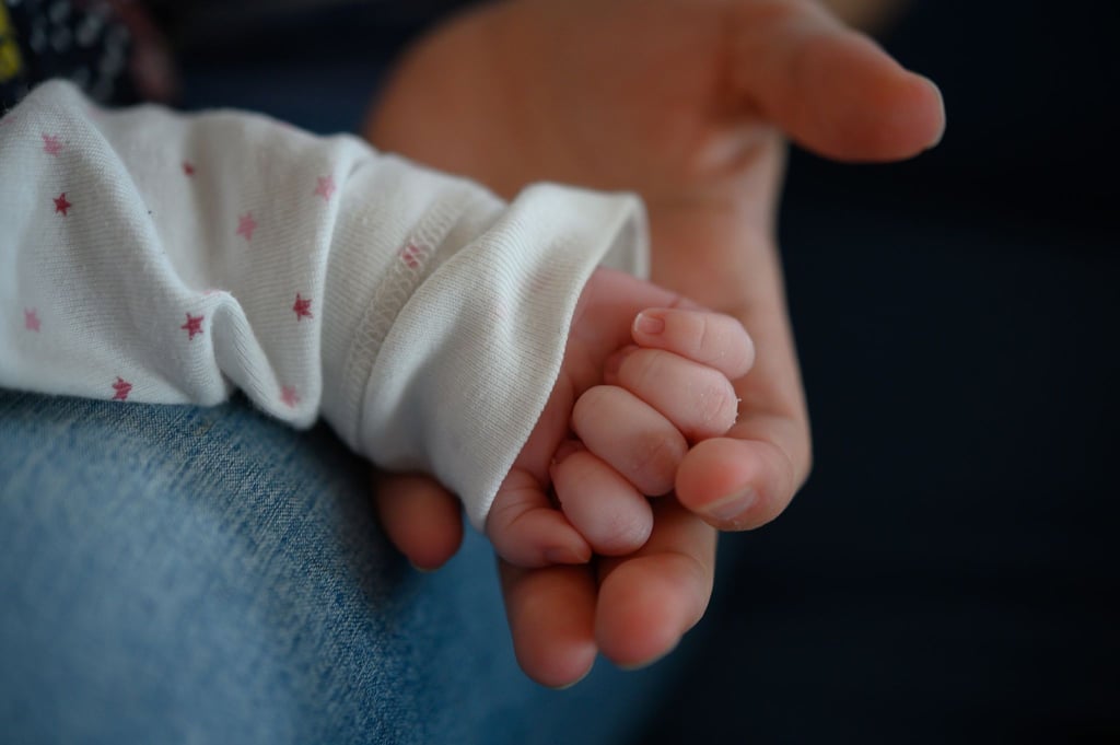 Eine Frau hält die Hand eines Babys.