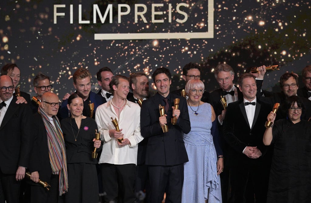 Zusammen mit Kulturstaatsministerin Claudia Roth (im blau-weiß gestreiften Kleid) stehen die Preisträger des Deutschen Filmpreises auf der Bühne.