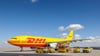 Ein Frachtflugzeug von DHL und verschiedene Fahrzeuge für die Logistik stehen auf dem Vorfeld auf dem Flughafen Leipzig/Halle.