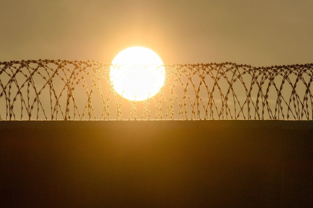 Die Sonne geht über der drahtbewährten Mauer der Justizvollzugsanstalt Burg auf.