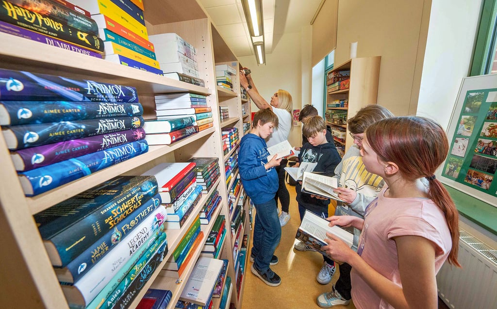 Deutschlehrerin Gerit Scherotzki stöbert mit den Kindern im Bücherregal. Ab nächstem Schuljahr ist das fest im Stundenplan verankert.