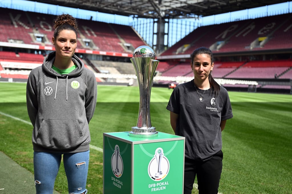 Janssen (l) vom VfL Wolfsburg und Hasret Kayikçi vom SC Freiburg stehen neben dem DFB-Pokal der Frauen im RheinEnergieStadion.