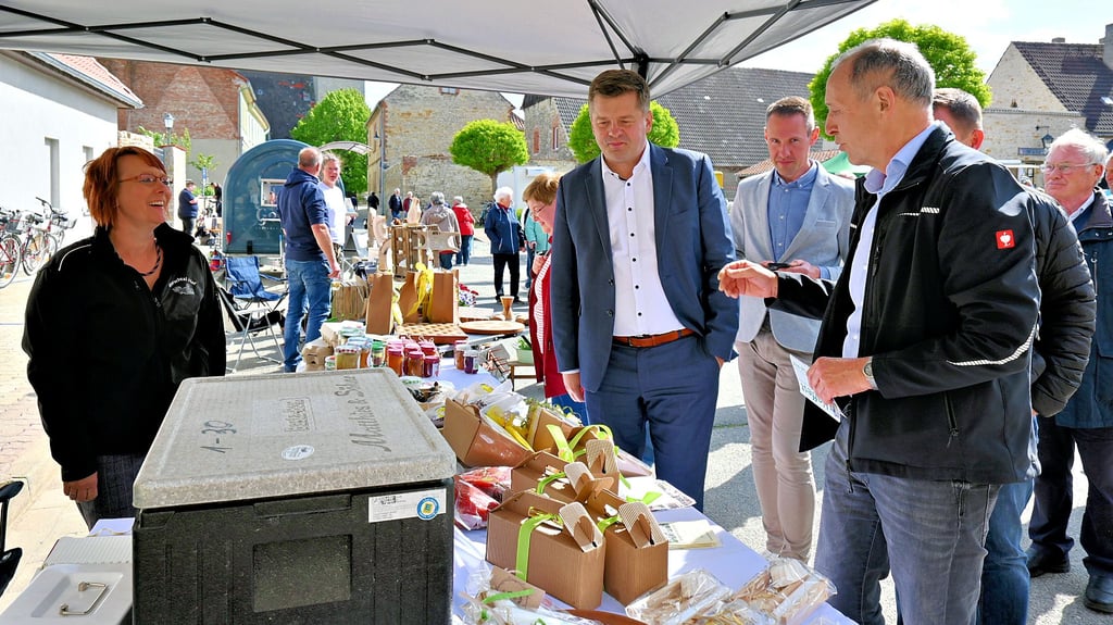 Minister Sven Schulze, Bürgermeister Fabian Stankewitz und Vertreter der AMG unternahmen einen Bummel über den Gröninger Feierabendmarkt.