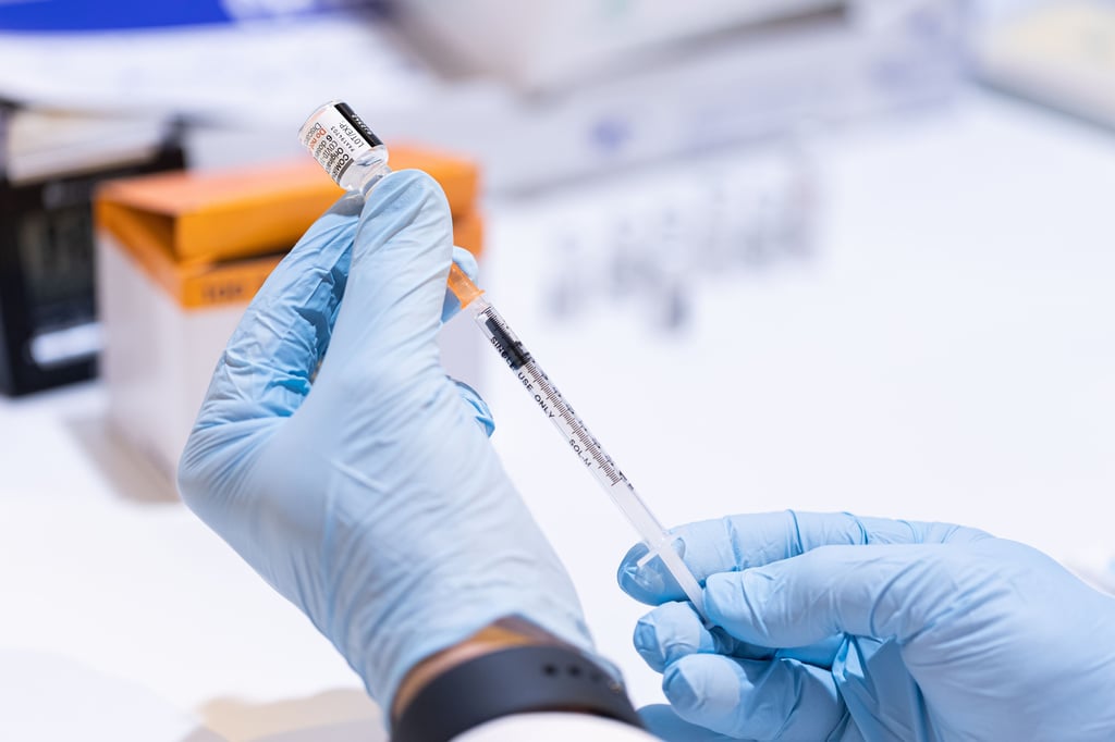 Ein Mitarbeiter eines mobilen Impfteams vom Arbeiter-Samariter-Bund (ASB) zieht eine Spritze mit dem BA.4/BA.5-Impfstoff von BioNTech/Pfizer gegen das Corona-Virus (SARS-CoV-2) im Impfzentrum im Zoo Hannover auf.