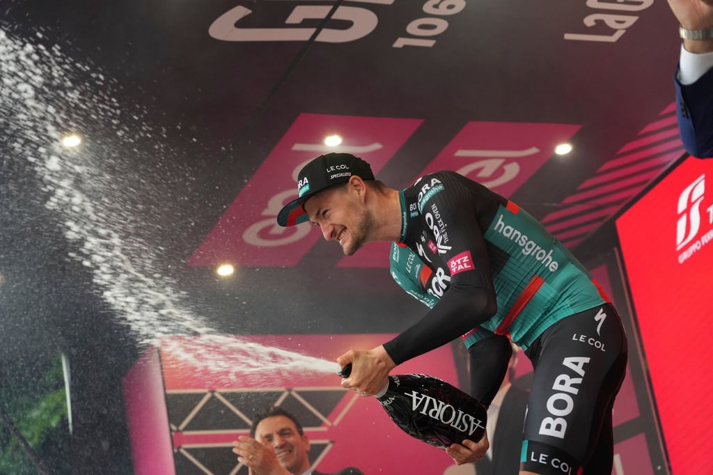 Der deutsche Radprofi Nico Denz vom Team Bora-hansgrohe feiert auf dem Podium seinen Etappensieg.