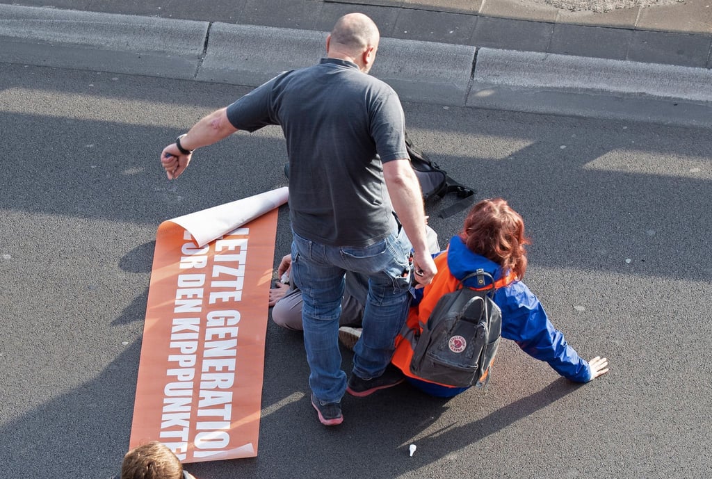 Bei einer Blockade der Gruppe Letzte Generation tritt ein Mann gegen einen Aktivisten.