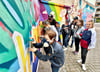 Nori (von links), Anna-Lotta, Moritz, Lara, Karl, Kimmy und Aaliyah gestalten mittels Graffiti Wände vor ihrer Grundschule in der Bernburger Talstadt. Unterstützt und angeleitet werden sie dabei von Hennig Hölemann (3. von links). 