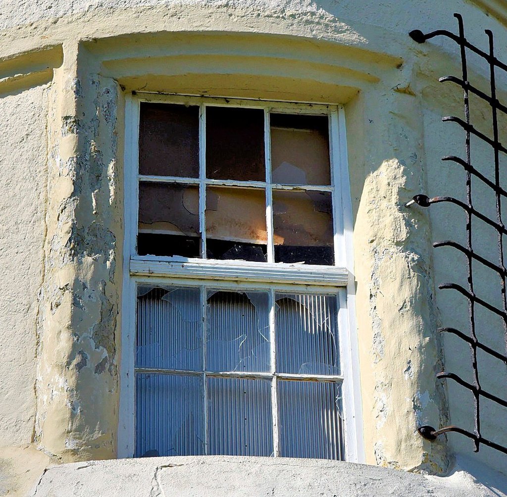 Weil die Scheiben eingeworfen wurden, stehen innen provisorische Verblendtafeln hinter dem Fenster.